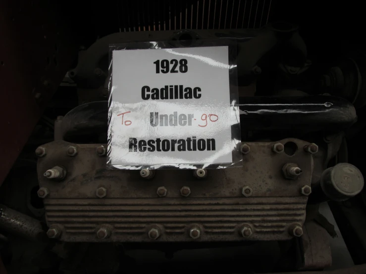 a cadillac under restoration sign hanging on an engine