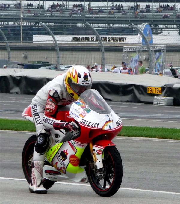 a man riding on the back of a motorcycle around a track