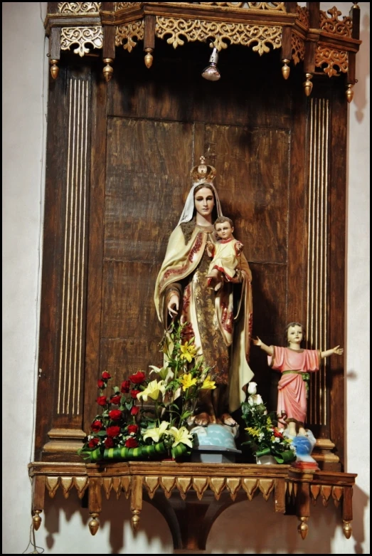 a statue of saint mary, in front of a wooden paneled wall
