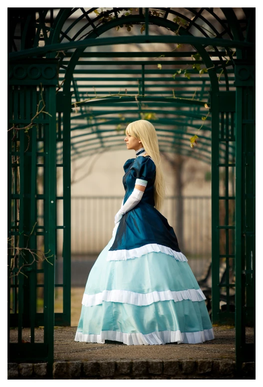 woman in teal and white dress walking under arbor