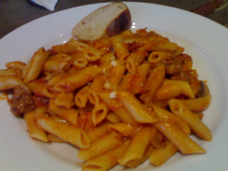 a pasta dish with sausage and parmesan cheese on the side