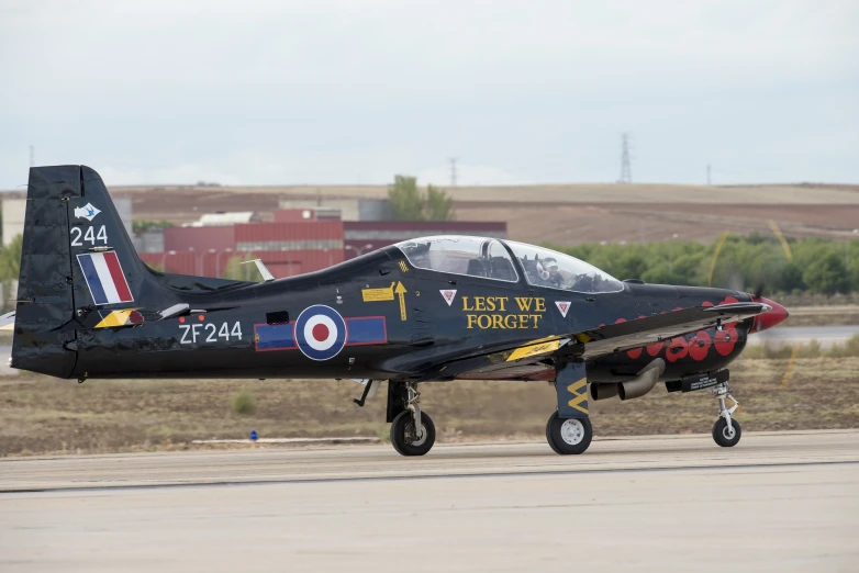 black and red fighter plane on runway with buildings in background
