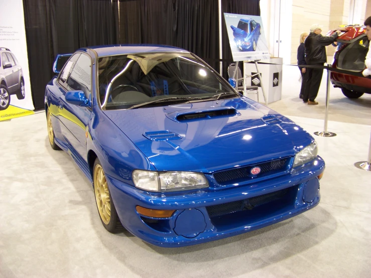 a blue car is parked on display in a room