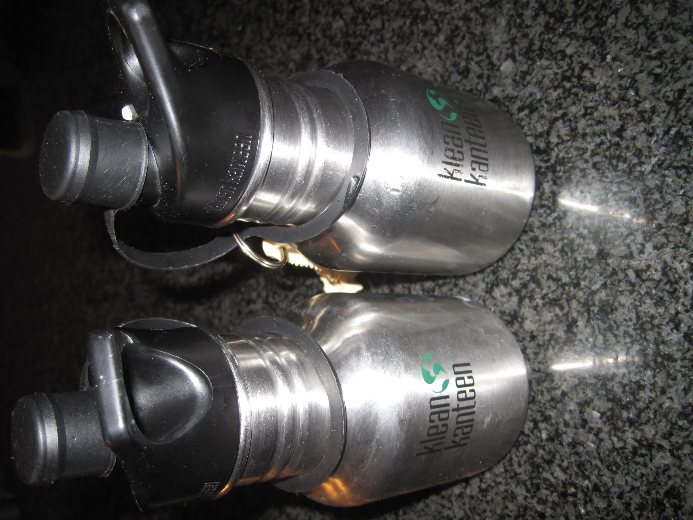 two stainless steel water bottles with caps and handles