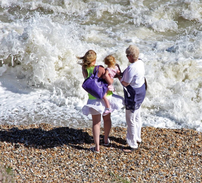 two women and a baby standing on a beach