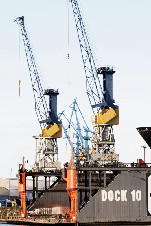 two large cranes are at dock near a ship