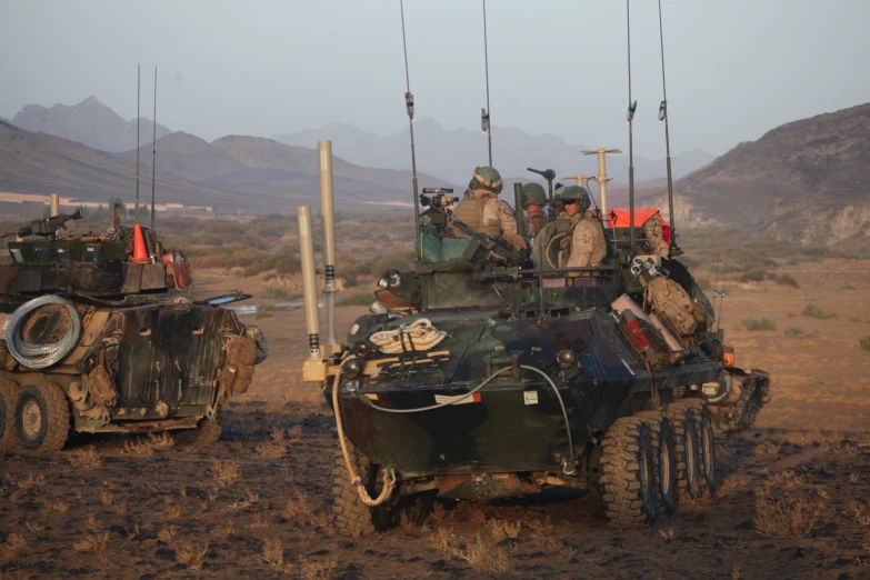 men and military equipment are riding on top of tanks