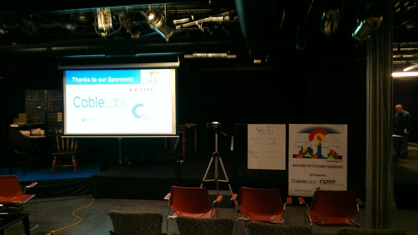 an empty lecture hall with chairs and projector screen