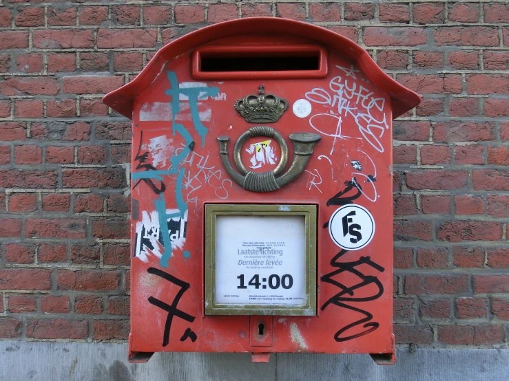 a red mailbox with graffiti on the side of a building