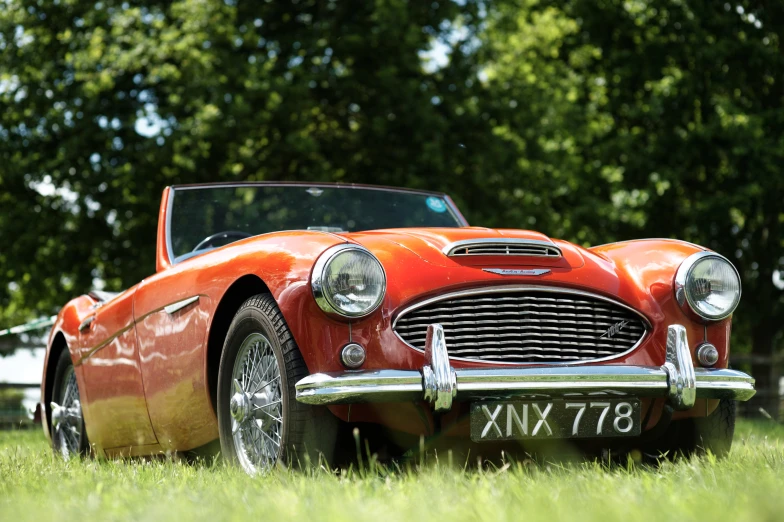 an old, restored sports car sitting in a grass field