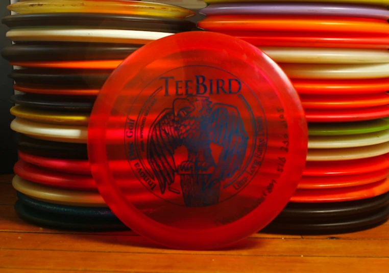 an orange frisbee that is sitting next to other multi - colored frisbees