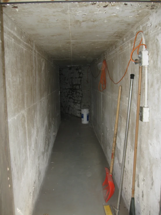 a very narrow concrete room with a light in the end