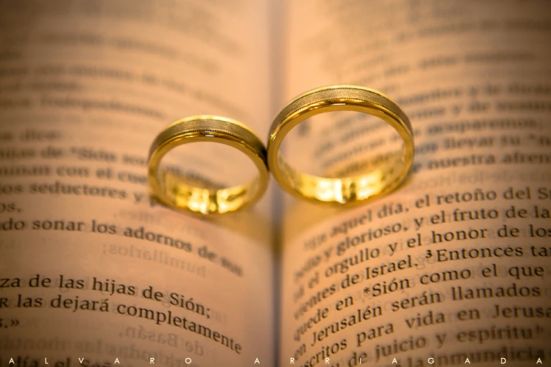 two wedding rings sitting in front of an open book