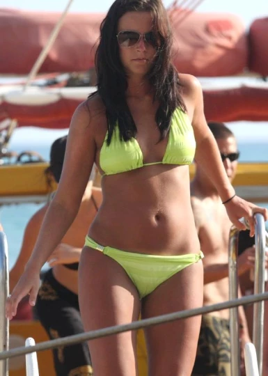 a woman is standing by a boat wearing a bikini