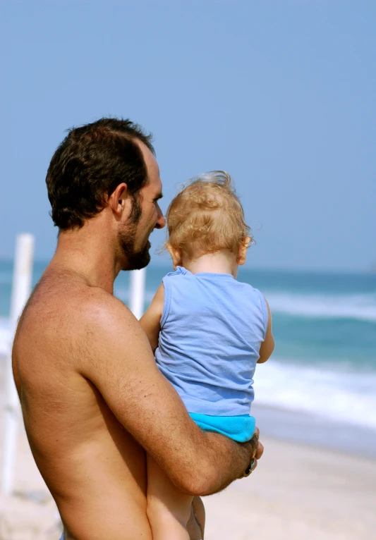 a man holding a little boy on a beach