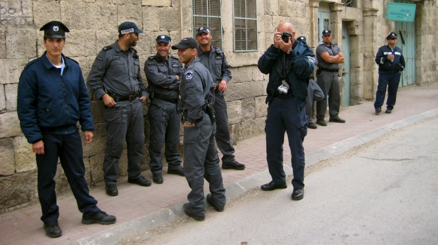 a group of policemen stand next to each other near a stone wall