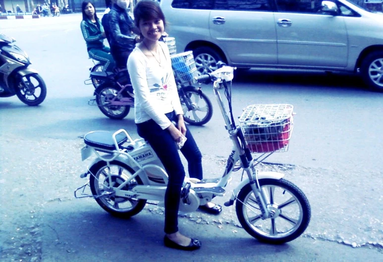 a girl sitting on top of a bicycle near other cars