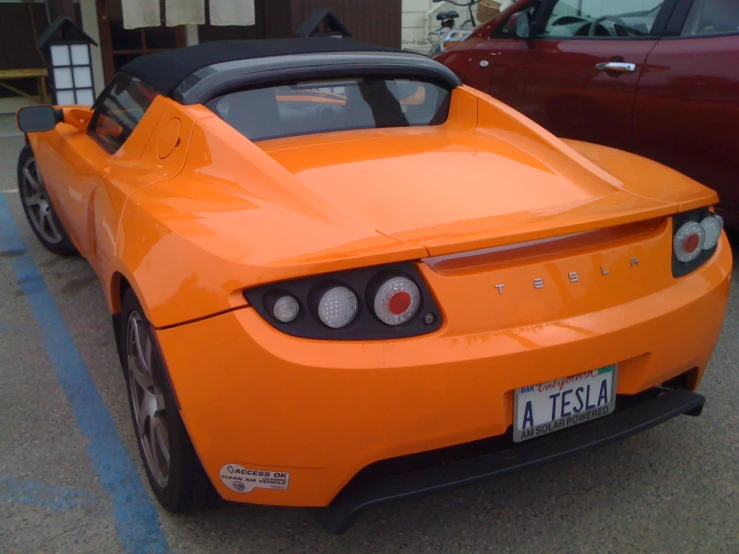 orange chevrolet car parked in a parking lot near a red car