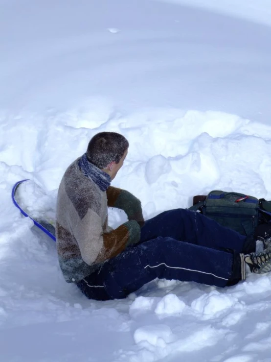 snow skier sitting in deep snow talking to someone