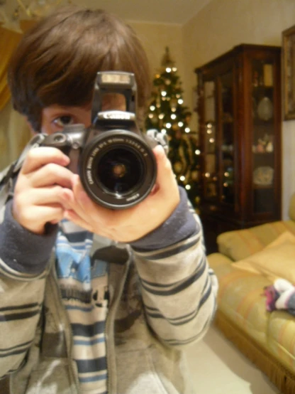 a boy is holding up a camera in a living room