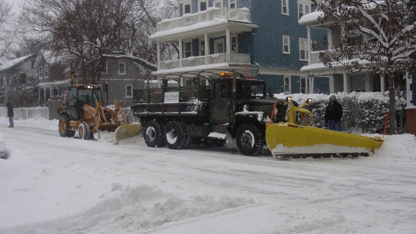 a large work truck and bull dozer are traveling in the snow