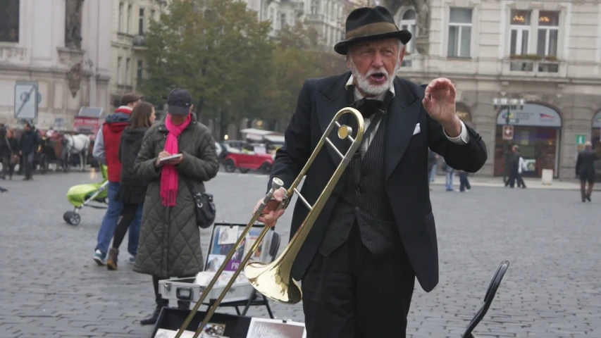an older man in black suit holding a trombone