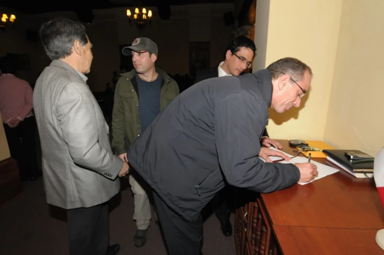 a group of men standing around a desk with papers