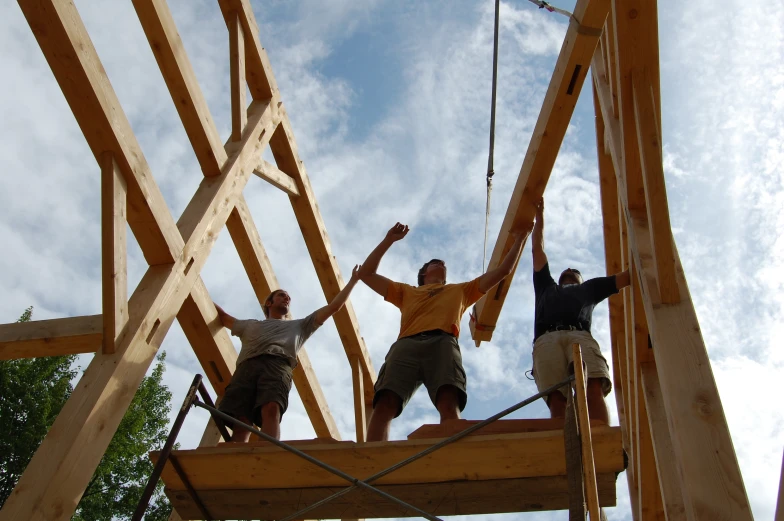 three men climbing up the construction walls of a building