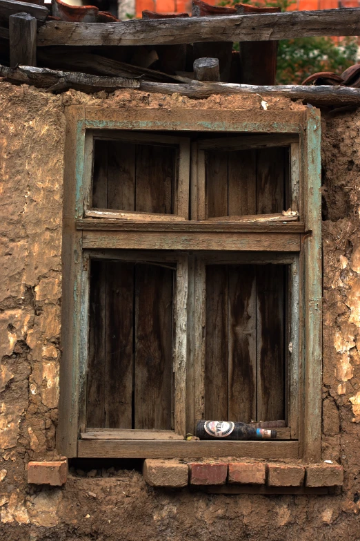 a window with an old wooden frame in an adobe building