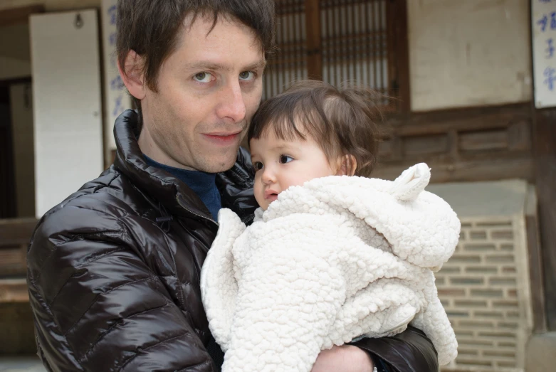 a man holding a child wrapped in a blanket