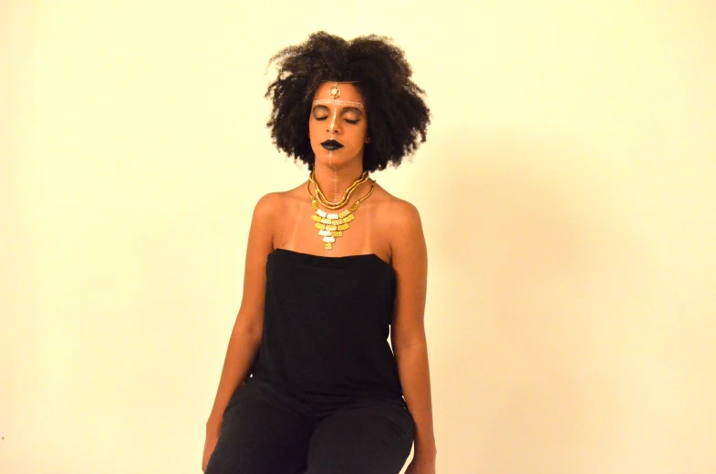 a woman with an afro has a necklace and black pants