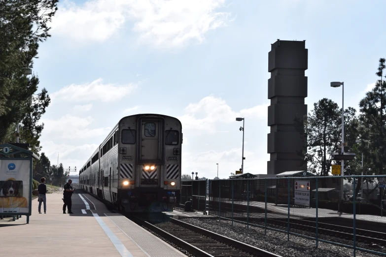 a train on tracks at a station with a person walking beside