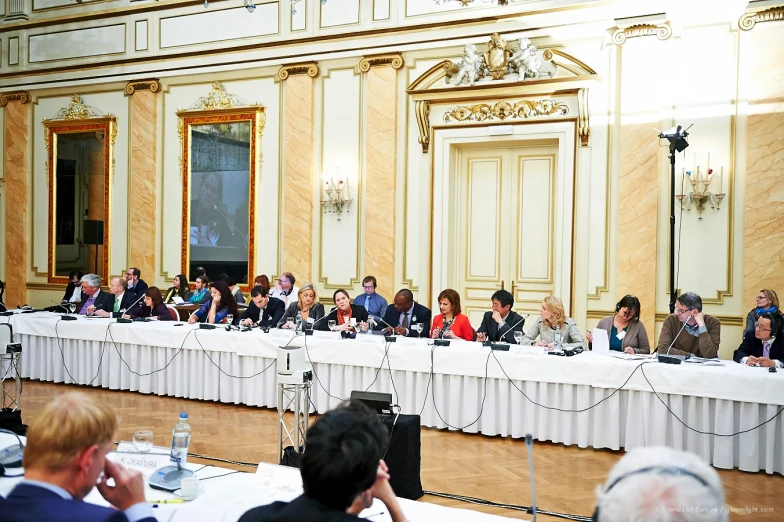 people sitting at long tables in front of microphones