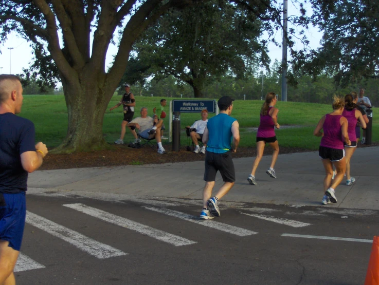 people running along the street while one person uses his phone