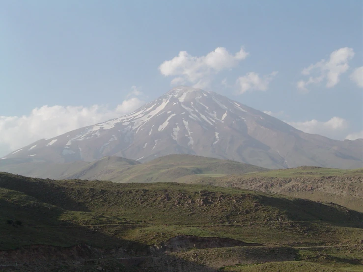 the large white mountain is surrounded by rolling hills