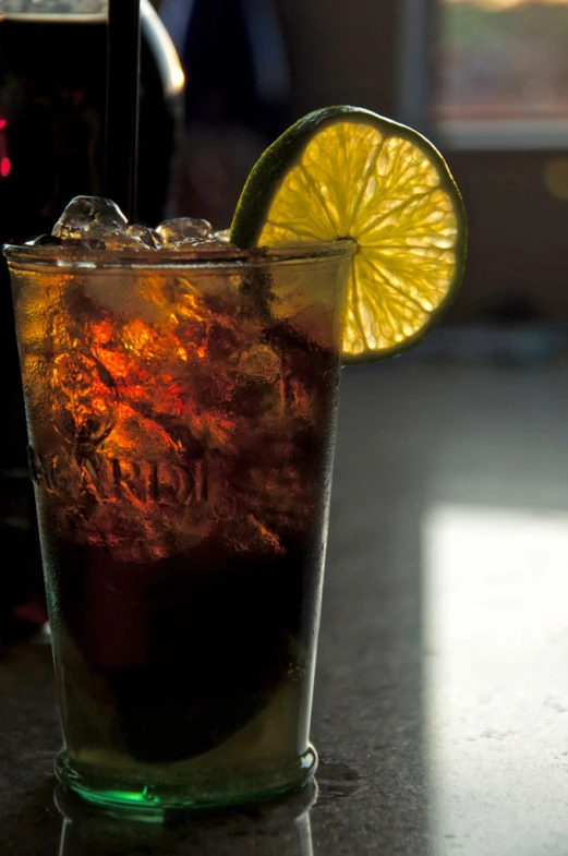 a glass filled with liquid with a lime slice on the rim