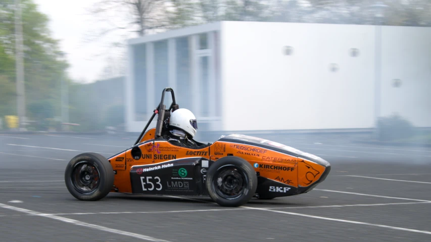 an orange car in a parking lot near a building