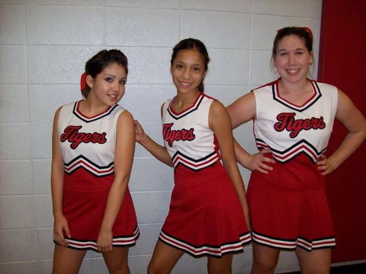 three s in cheerleader outfits posing for a po