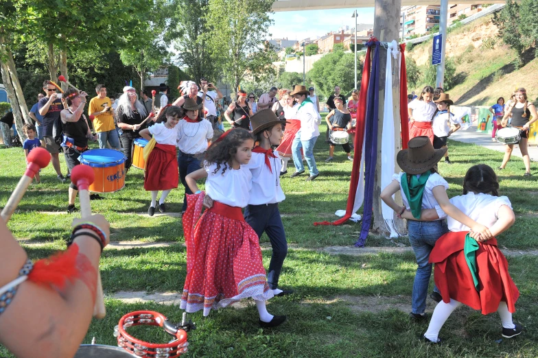 children in costume dance around in the grass