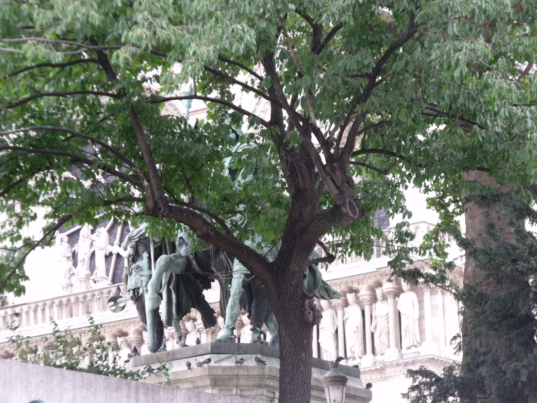 a statue of people holding children sitting on benches under trees