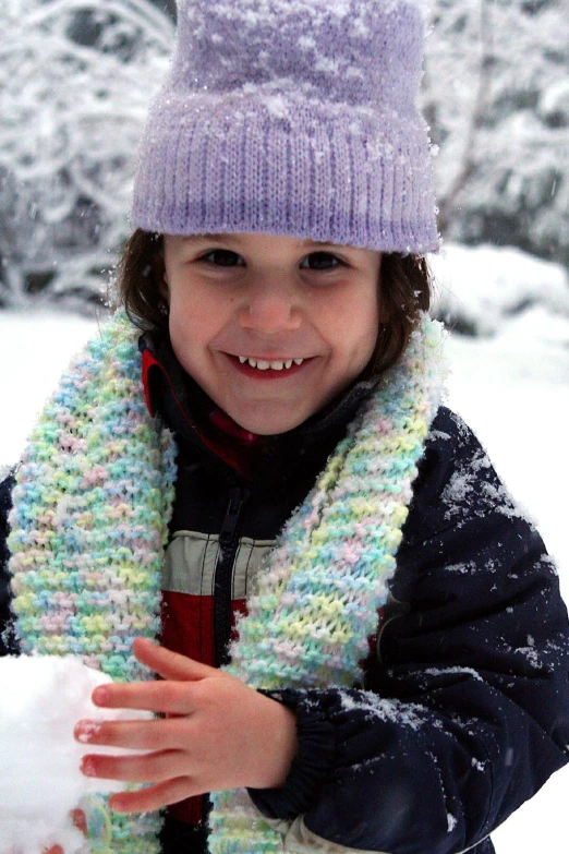 a young child smiles as she holds onto a glove