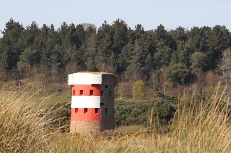 an orange and white tower sits next to a forest