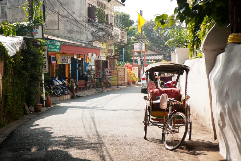 an asian rickshaw rides down a narrow street