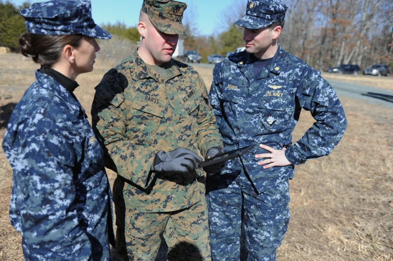 four military personnel stand in an open field