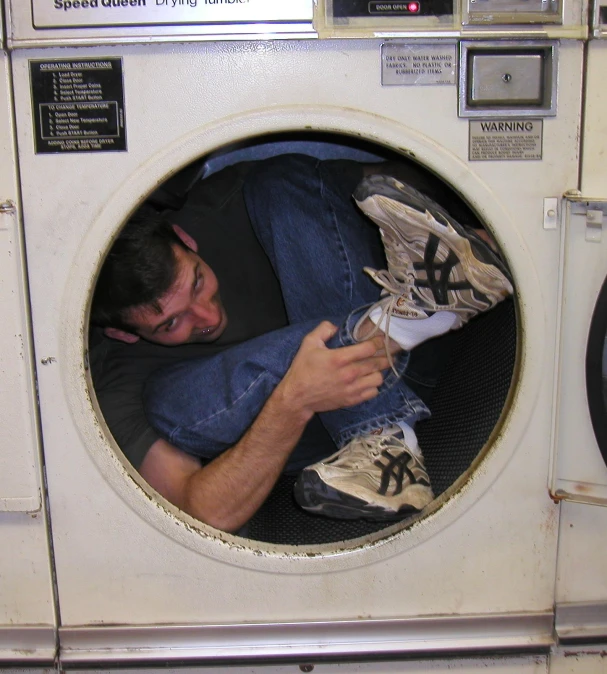 a man using a machine to do laundry on his clothes