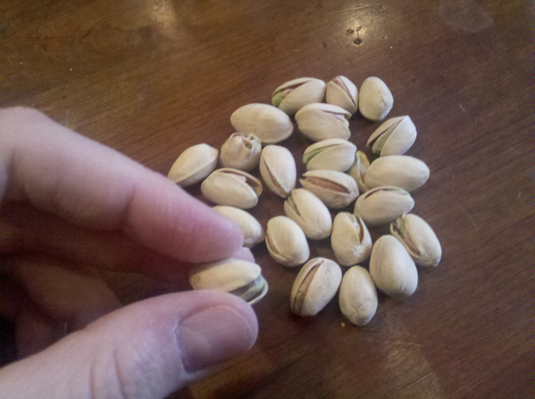 a hand holding almonds on top of a table