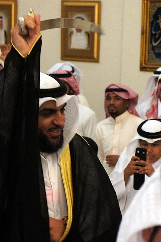 several people in traditional garb with one holding up a knife and the other pointing at it