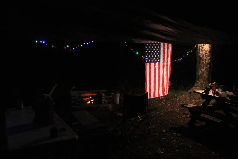 american flag hung on a tent by a fire pit