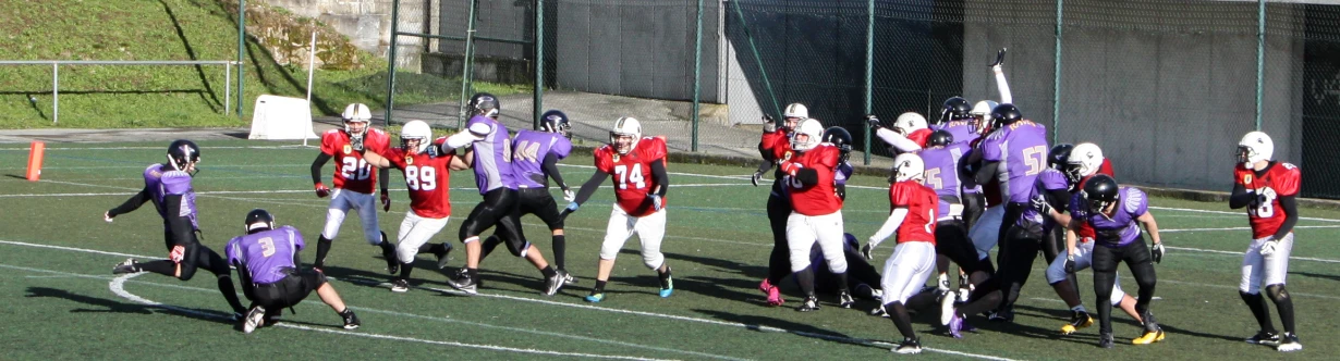 several players of different colors and numbers holding their football equipment and wearing helmets