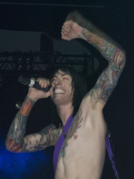 the man is shirtless, singing into a microphone